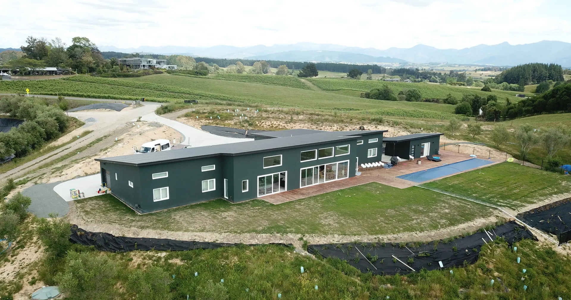 A dark-clad home set among vineyards in the Tasman landscape