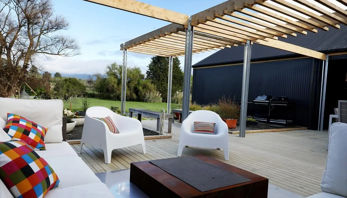 Pergola-covered outdoor lounge deck at The Black House, an Ecotectural home in Tasman