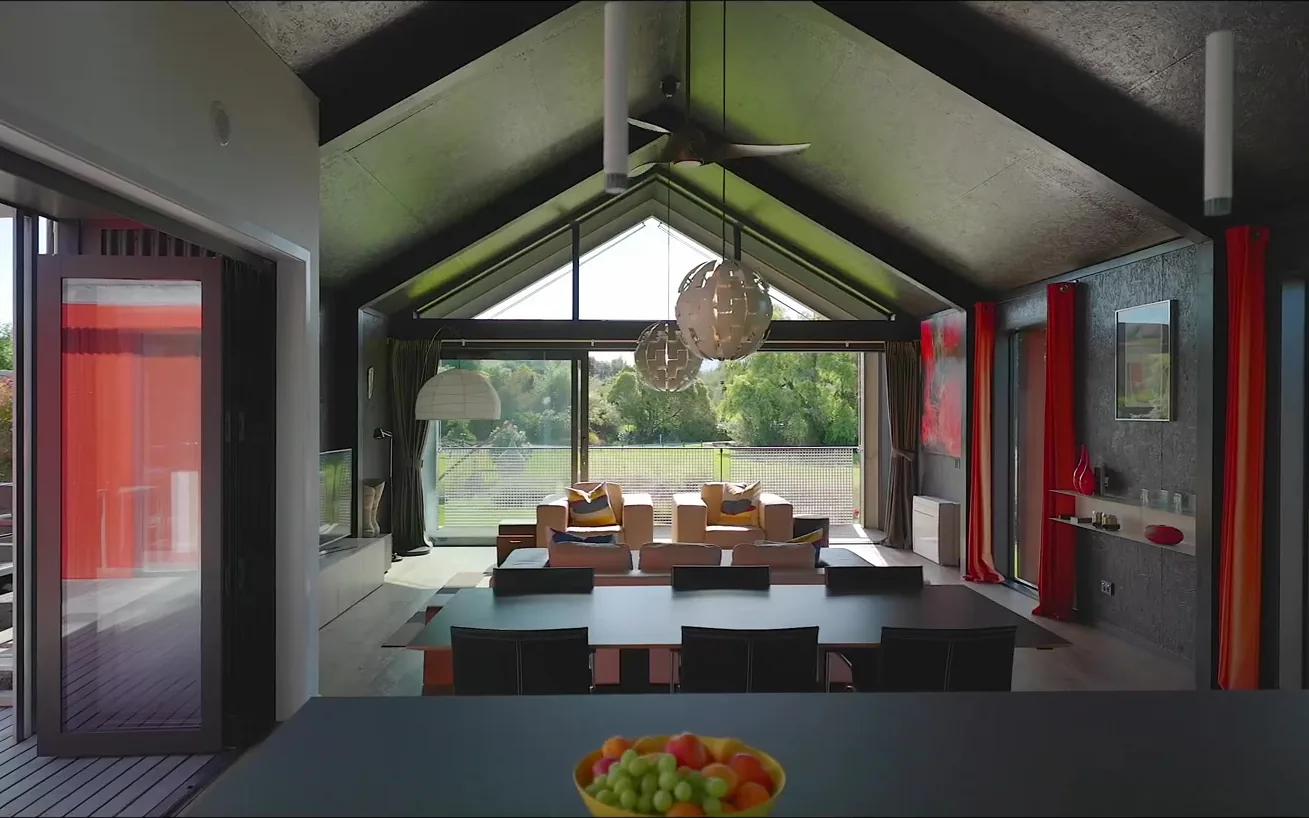 The vaulted living and dining space inside The Black House, opening through bifold doors to the spa deck