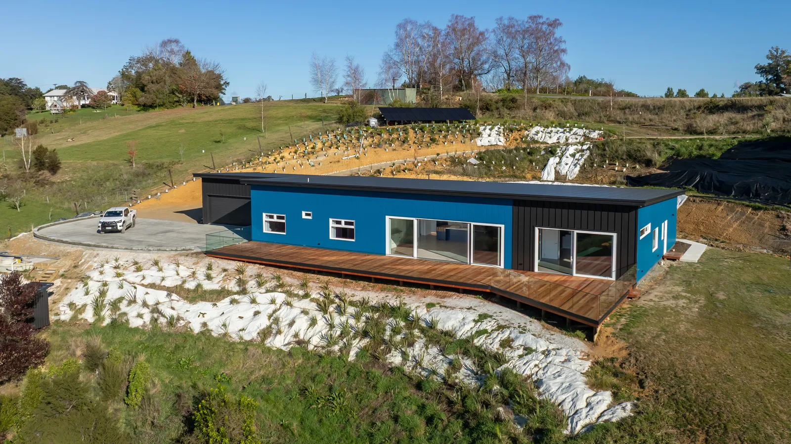 Aerial view of the Blue House, an Ecotectural coastal home with blue vertical cladding and a hardwood deck