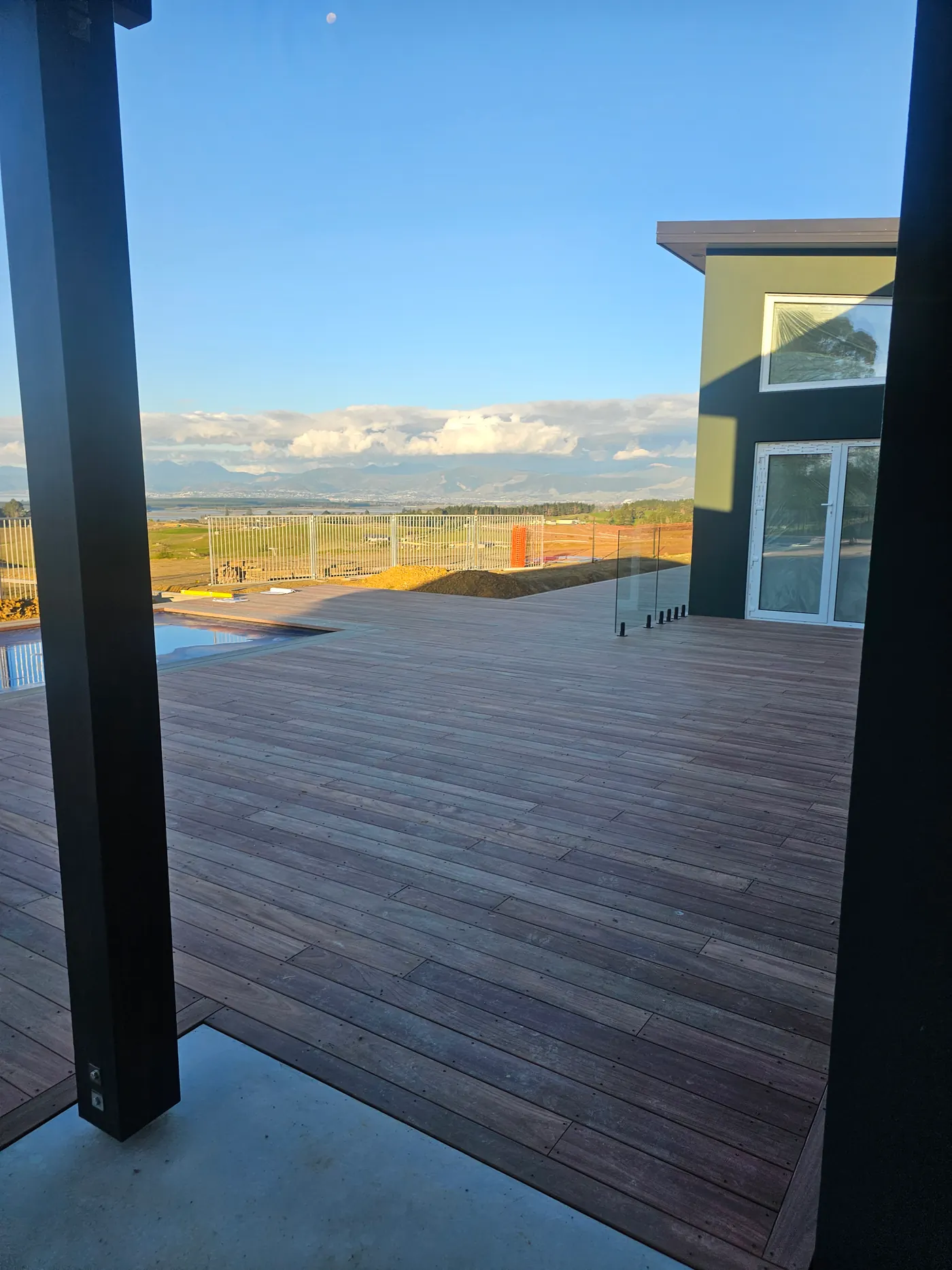 Timber deck looking out through glass to the Waimea plains and mountains beyond, an Ecotectural home