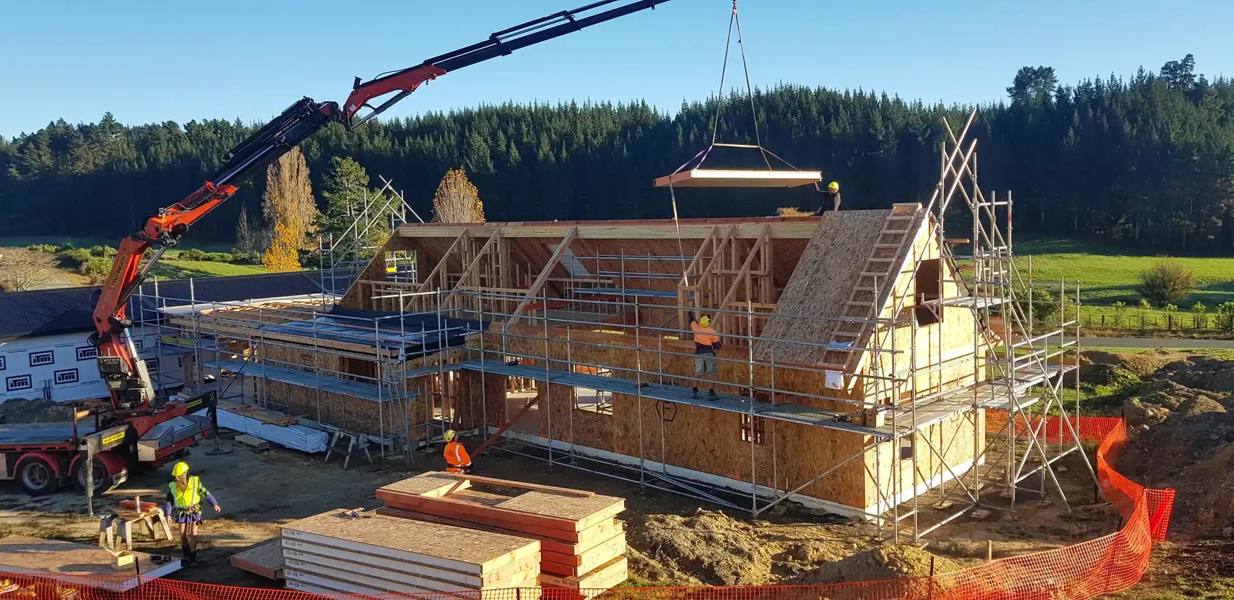 Craning a prenailed timber frame panel into place on an Ecotectural build