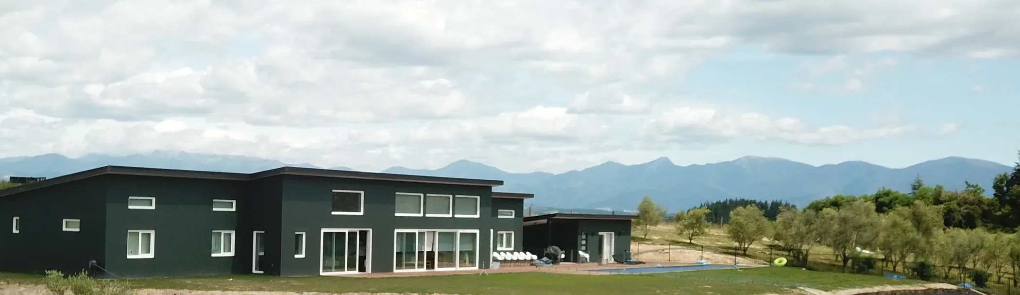 Dark-clad Ecotectural home on a rural Moutere hillside site with the mountain range behind