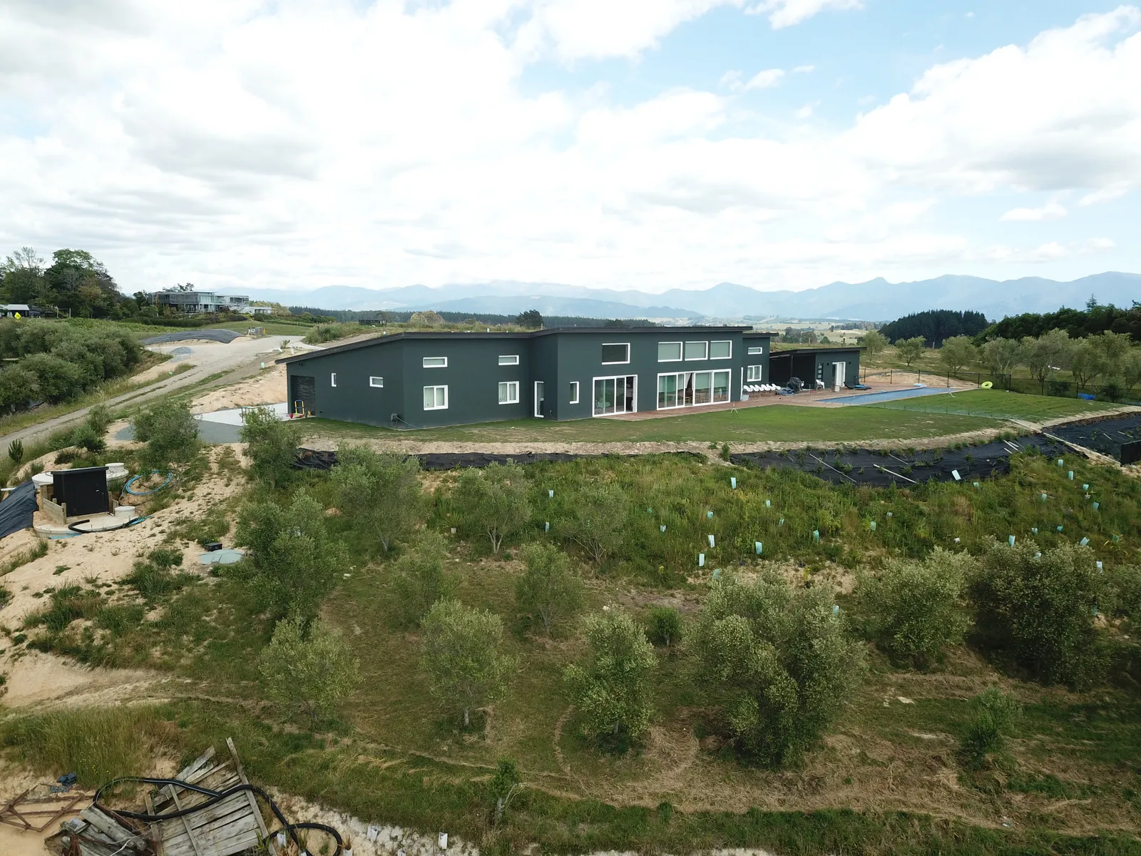 Aerial view of the Green House, an Ecotectural home set among rolling Tasman countryside and hills