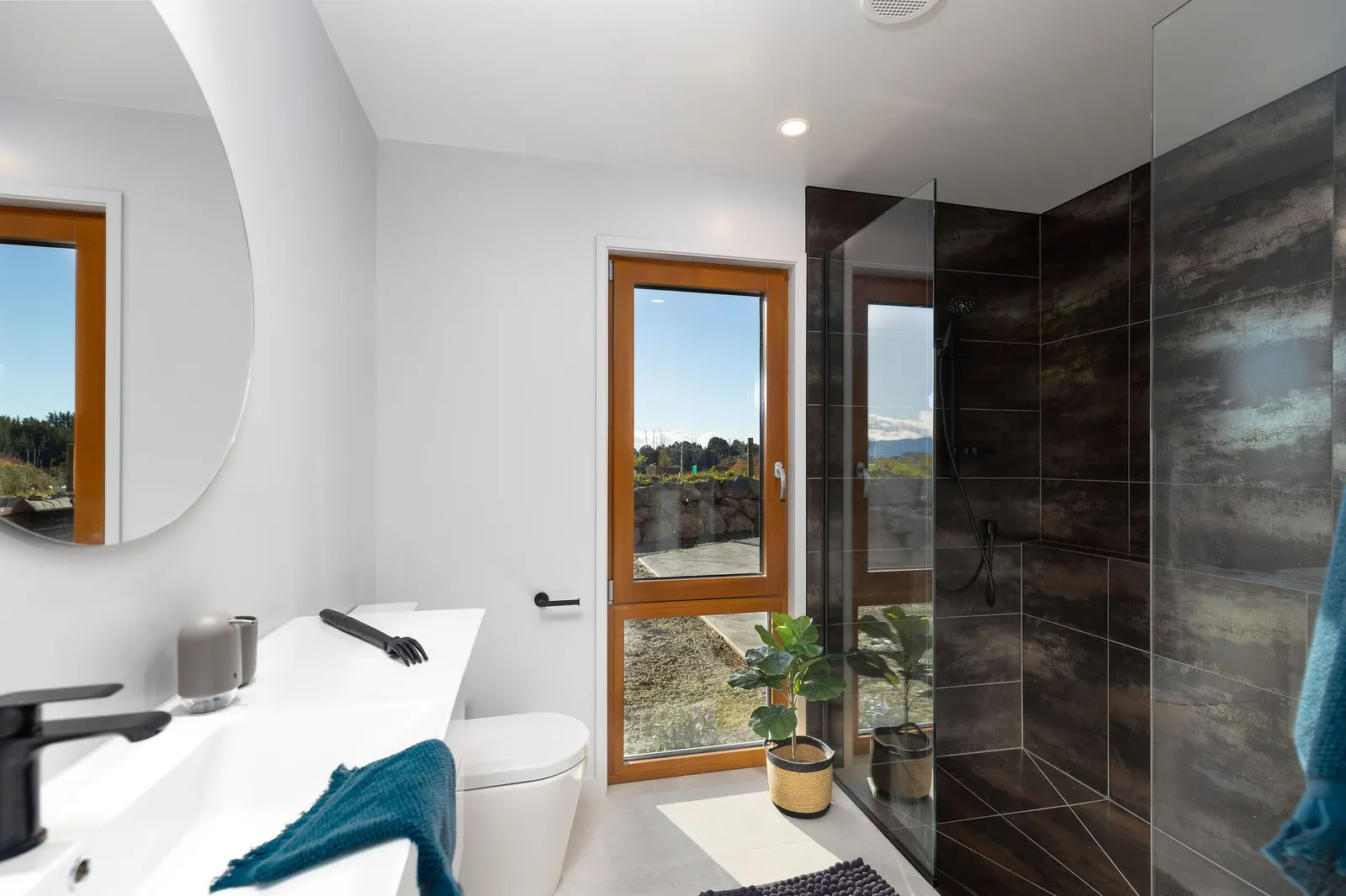 Bathroom with warm timber joinery and a view to the Tasman hills, Passive Home at Horton Road