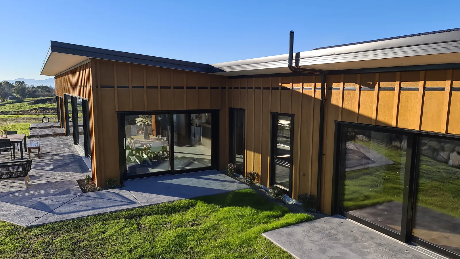 Timber board-and-batten facade and black-framed glazing at Horton Road, an Ecotectural home in Tasman