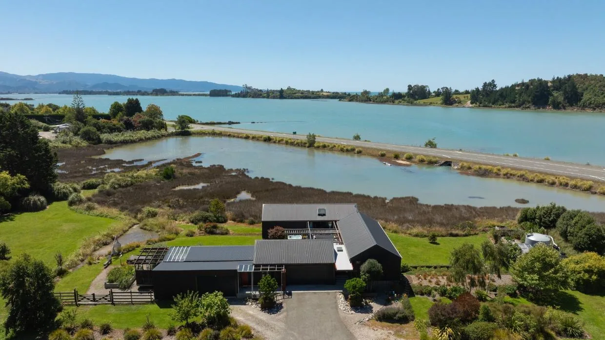 Aerial view of The Black House above the estuary, Tasman
