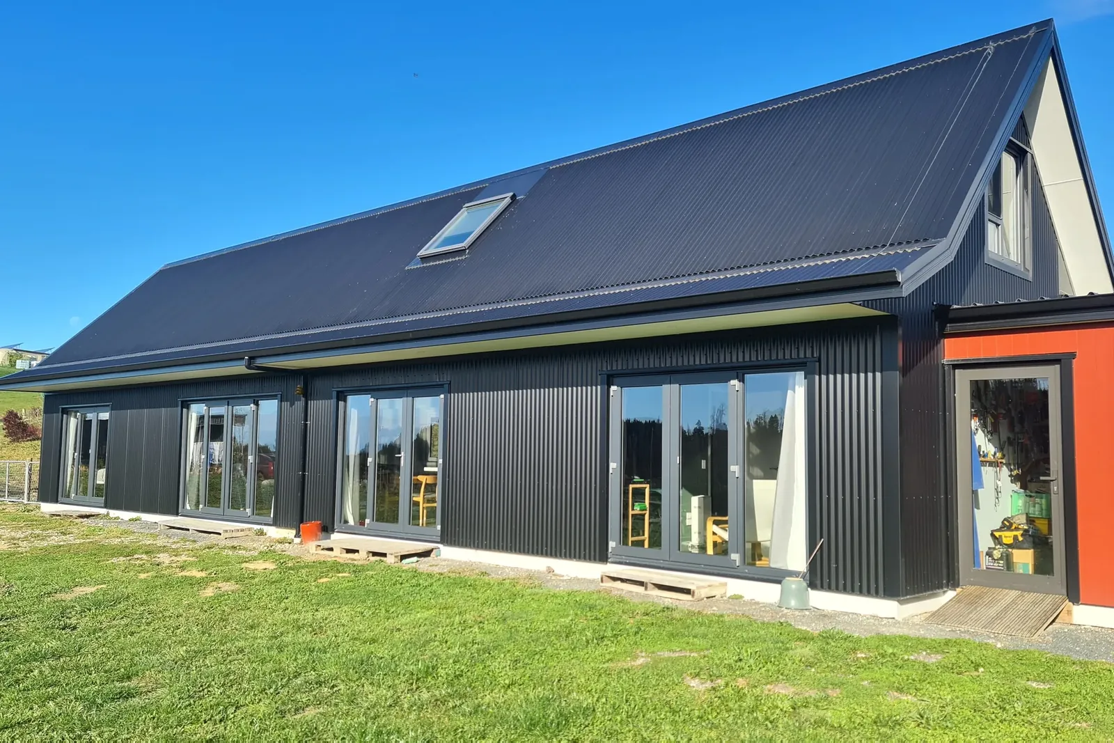 The finished long, gable-roofed home in black long-run corrugate at Martin Conway, Redwood Valley