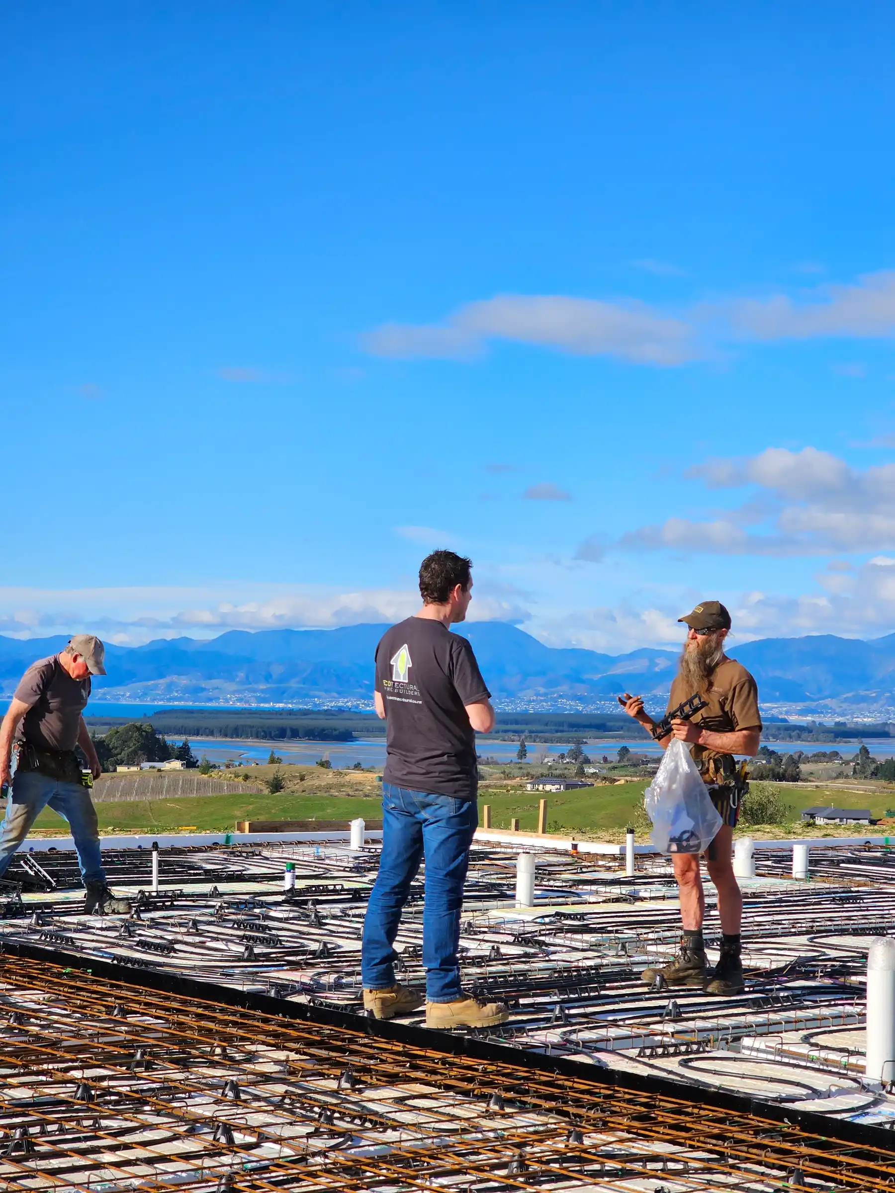 The Ecotectural team talking on an insulated foundation slab on a hilltop site above Tasman Bay