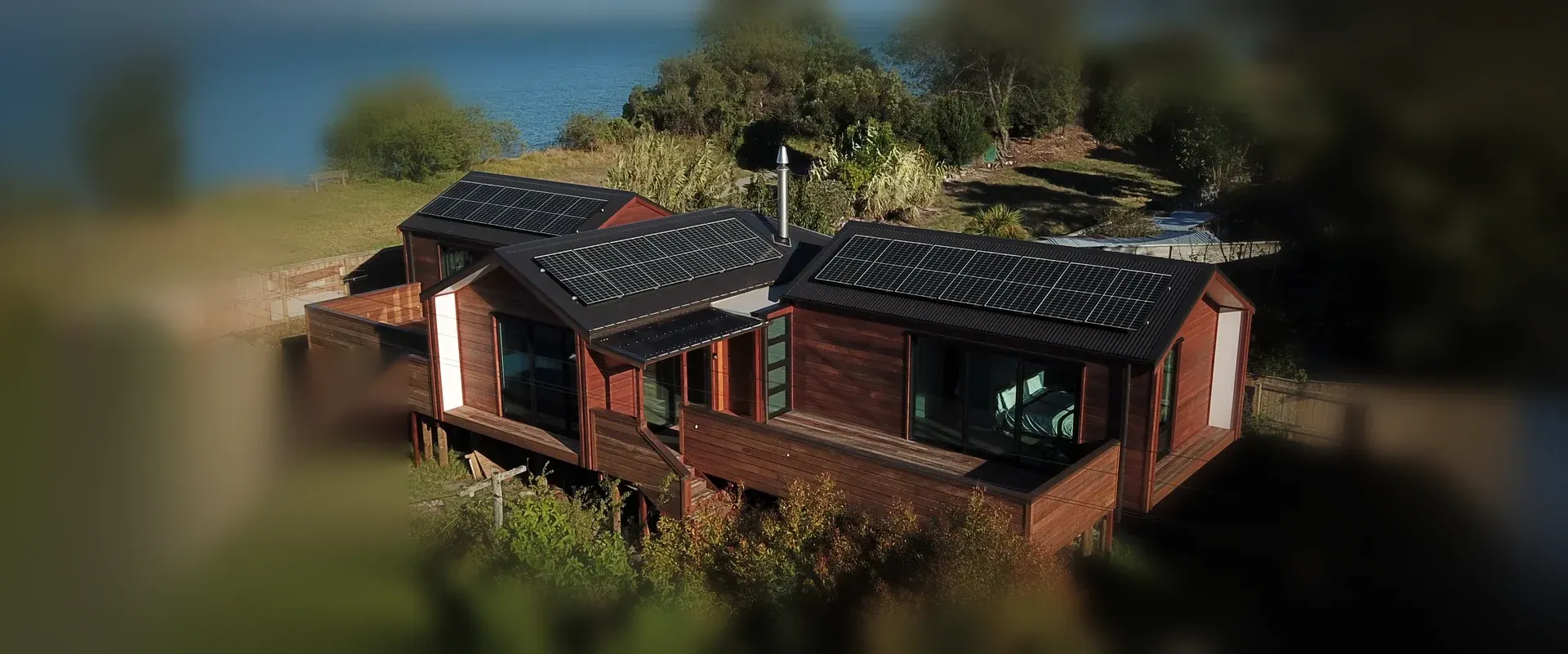 Aerial view of The Cedar House, the cedar-clad solar home above the Motueka estuary