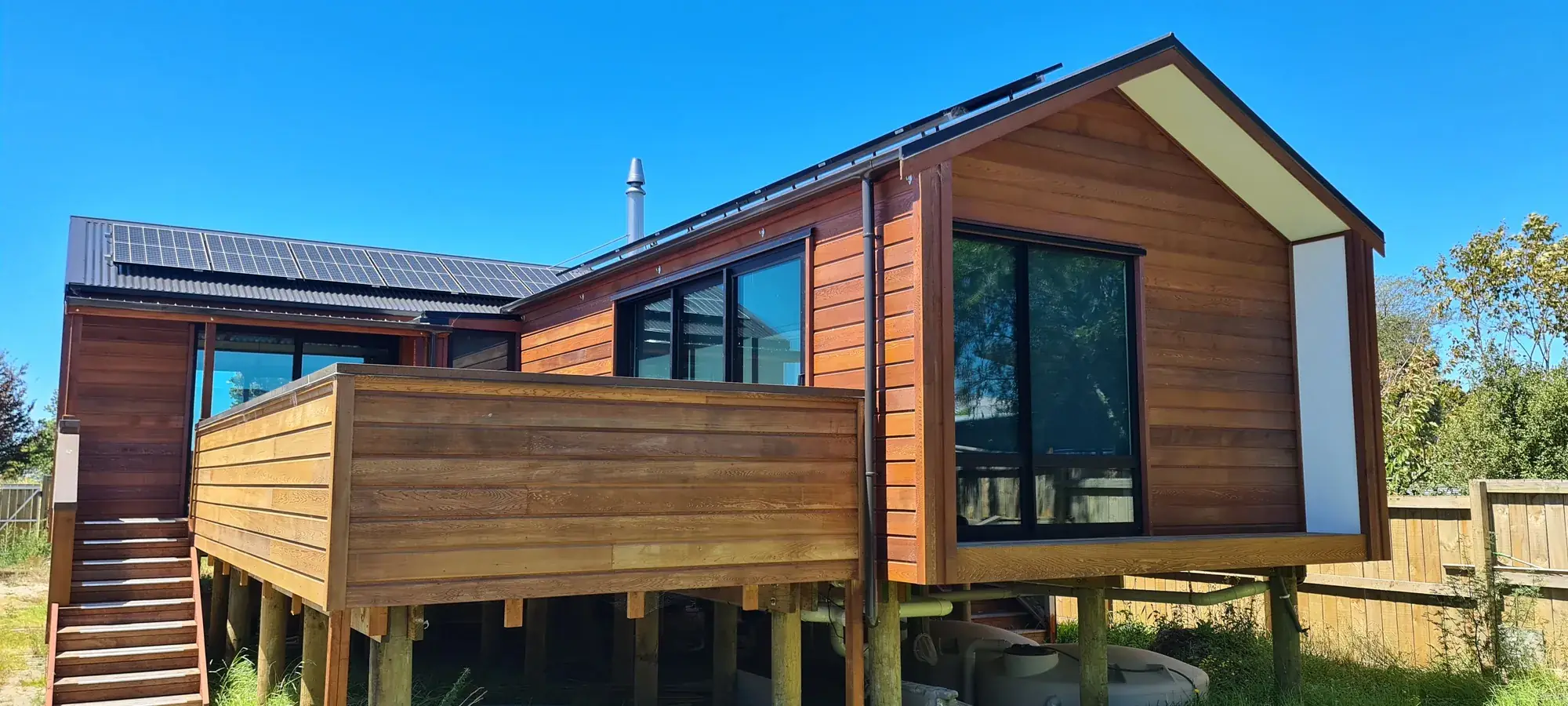 The Cedar House lifted on piles above its sloping Motueka site
