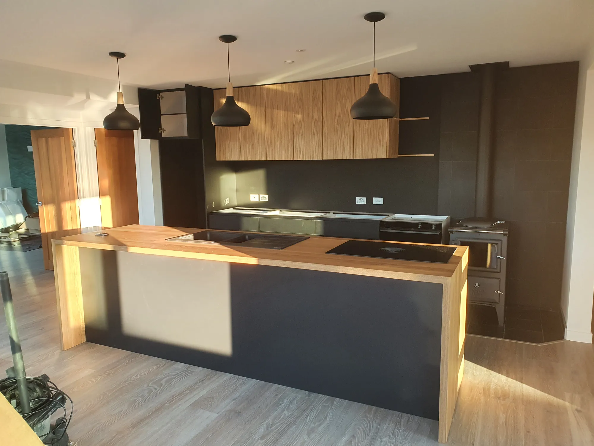 Black and oak kitchen with pendant lights and a timber island at The Cedar House, Motueka