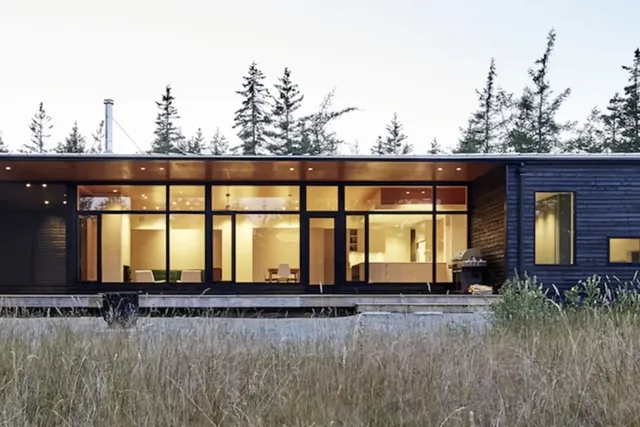 Dark-clad architectural home at dusk with warm-lit windows, Nelson Tasman