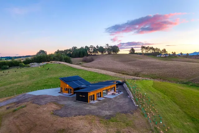 Aerial view at dusk of an Ecotectural home in the rolling Tasman farmland, the Projects page hero