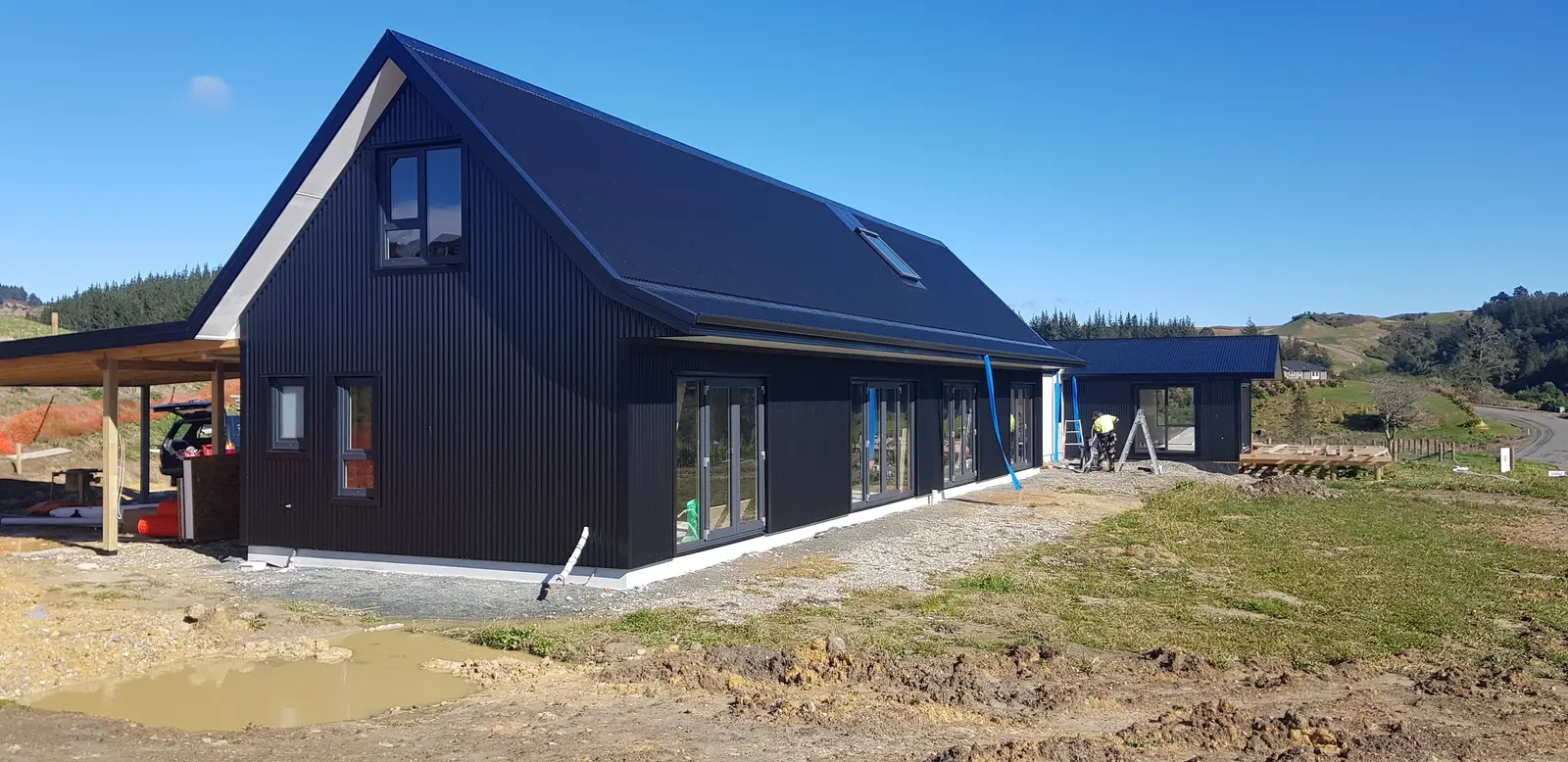 The black corrugate SIPs home nearing completion on its rural Redwood Valley site