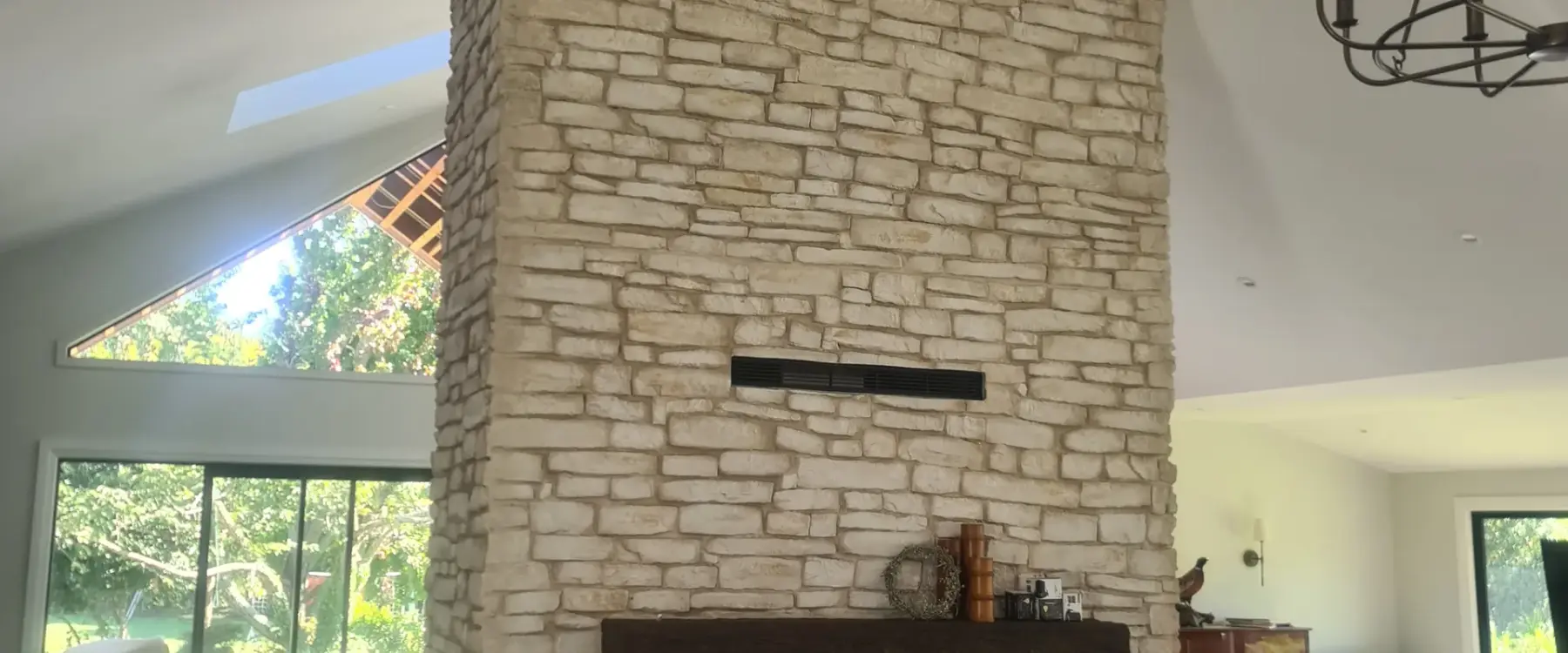 Double-height stacked-stone fireplace in the renovated living space at Paton Road