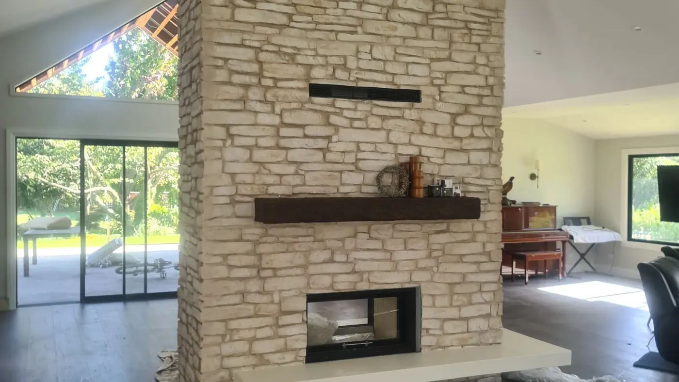 The double-sided firebox and timber mantel in the stacked-stone fireplace at the Paton Road renovation