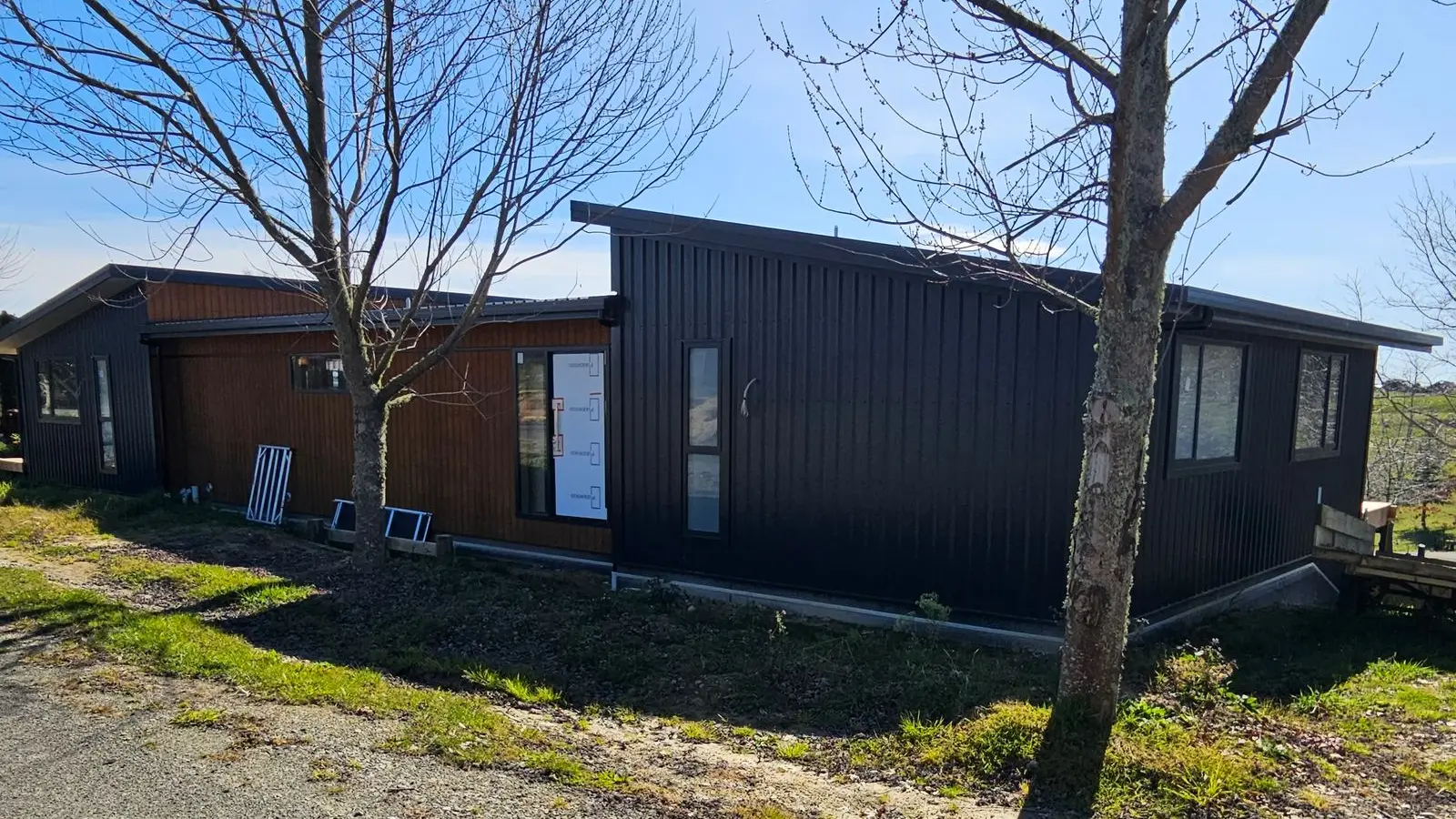 Dark cladding and timber entry at the split-level home set into its slope at Pipin Lane, Tasman