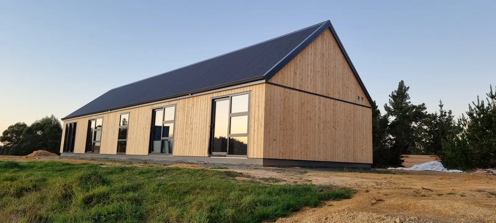 The long timber side elevation of the home in evening light, Redwood Valley