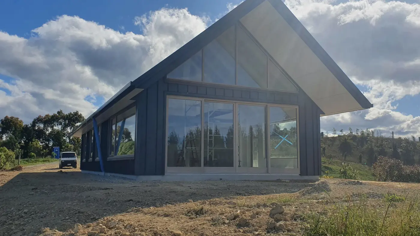 Custom gable home under a big Tasman sky, built by Ecotectural on a hillside platform